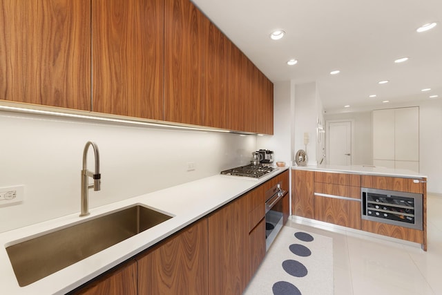 kitchen with stainless steel appliances, a sink, light countertops, brown cabinets, and modern cabinets