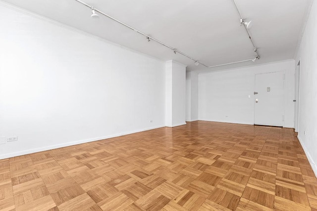 unfurnished room featuring baseboards and track lighting