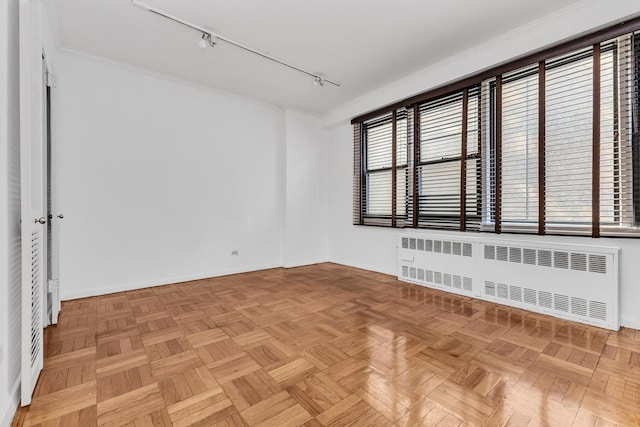 unfurnished room with baseboards, rail lighting, and radiator heating unit