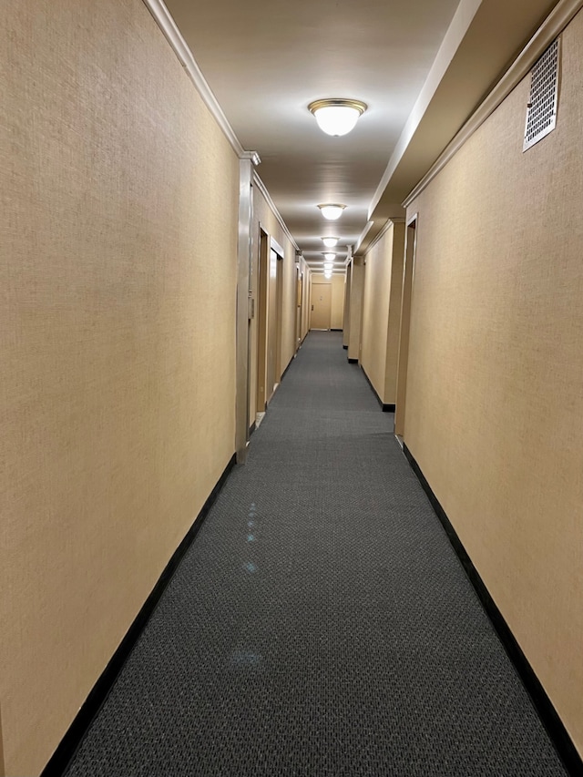 corridor with baseboards, dark carpet, visible vents, and crown molding