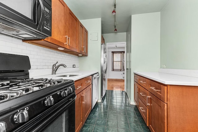 kitchen featuring dark tile patterned flooring, brown cabinets, backsplash, black appliances, and a sink