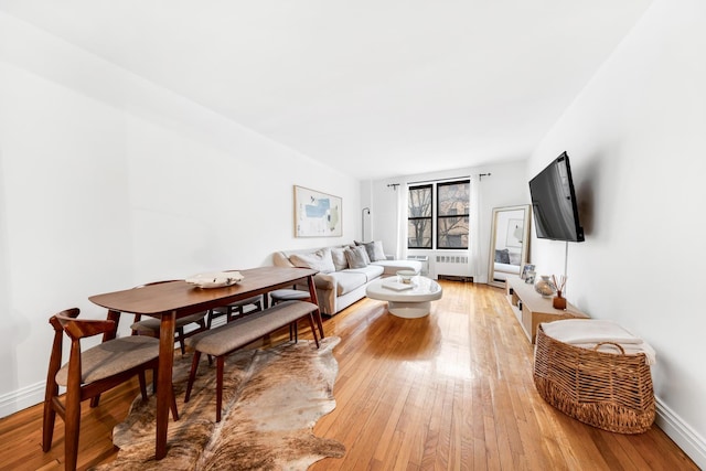 living area with radiator, light wood-style floors, and baseboards