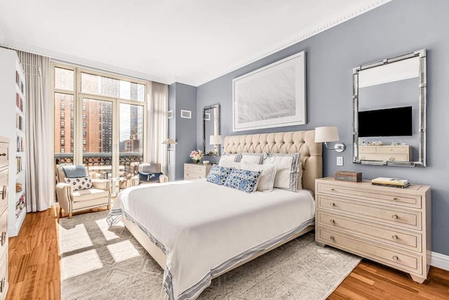 bedroom featuring light wood-style floors, baseboards, and floor to ceiling windows