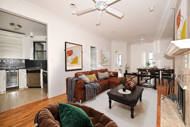 living room featuring beverage cooler, light wood-type flooring, ceiling fan, and crown molding