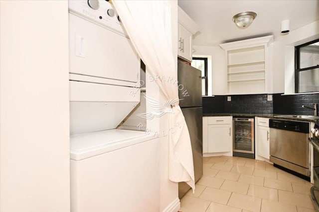 washroom with stacked washer / drying machine, beverage cooler, and light tile patterned floors