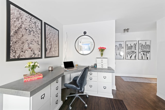 office featuring built in desk, dark wood-type flooring, and baseboards