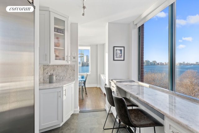 dining area featuring baseboards, built in study area, rail lighting, expansive windows, and a city view