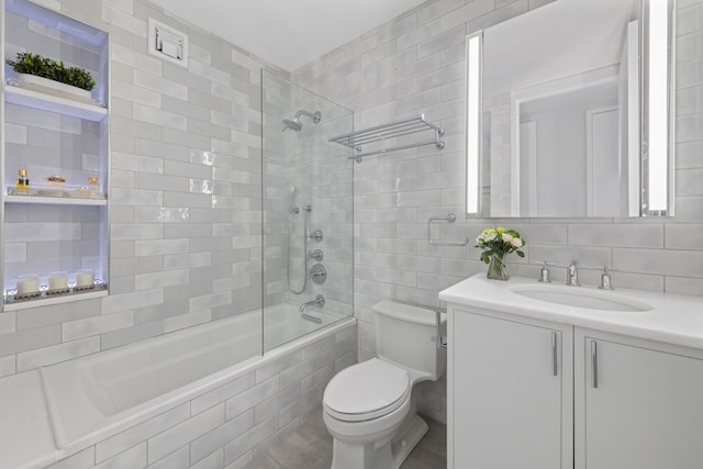 full bath with toilet, backsplash, tiled shower / bath combo, vanity, and tile walls