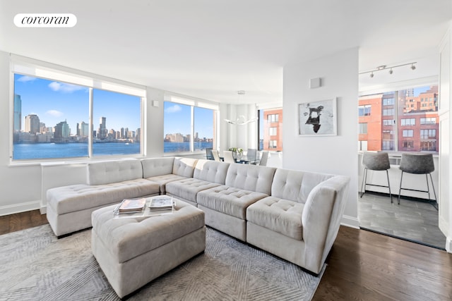 living area with visible vents, rail lighting, wood finished floors, a view of city, and baseboards