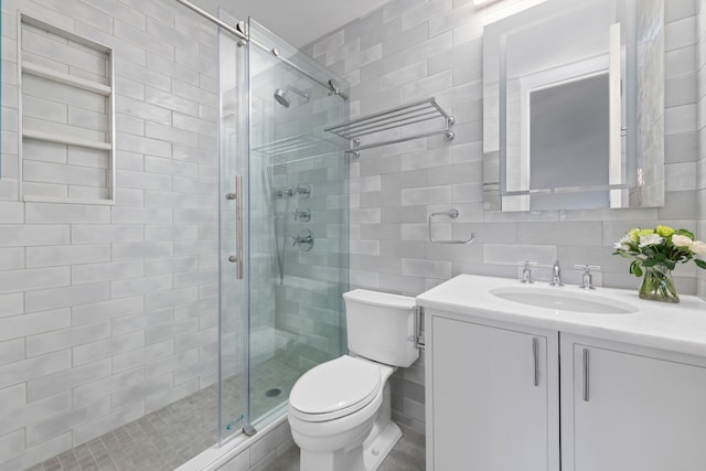 bathroom featuring toilet, vanity, tile walls, a shower stall, and tasteful backsplash