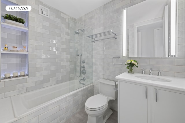 bathroom featuring backsplash, tile walls, vanity, toilet, and tiled shower / bath combo