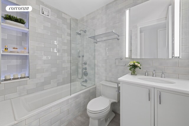 21 S End Ave Unit 722, New York City, NY 10280 - bathroom featuring backsplash, tile walls, vanity, toilet, and tiled shower / bath combo