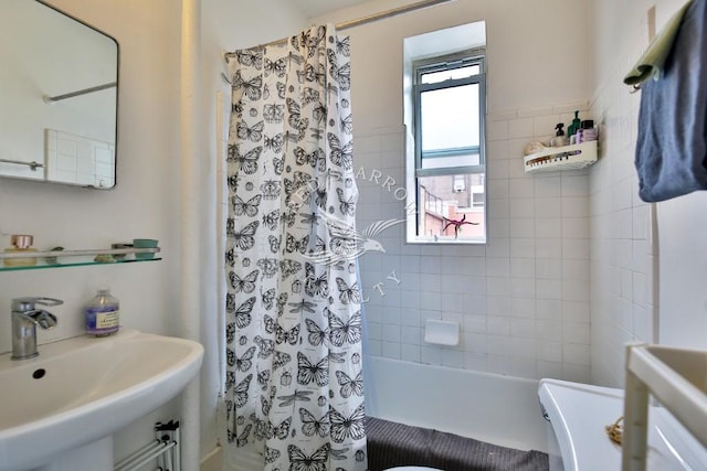 bathroom with shower / bath combo with shower curtain and a sink