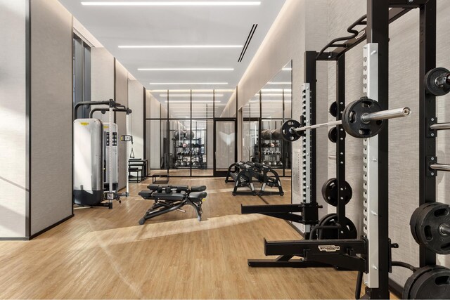 exercise room with a wall of windows and wood finished floors