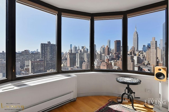 sunroom / solarium featuring a baseboard heating unit and a city view