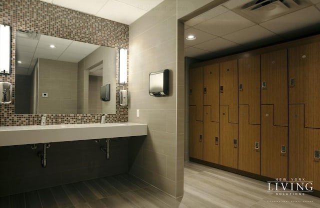 bathroom featuring visible vents, decorative backsplash, and tile walls