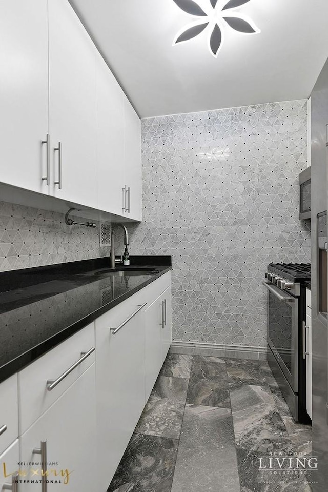 kitchen featuring stainless steel appliances, marble finish floor, white cabinetry, and a sink