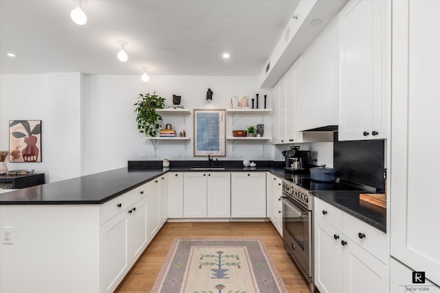 kitchen with dark countertops, a peninsula, open shelves, and stainless steel stove