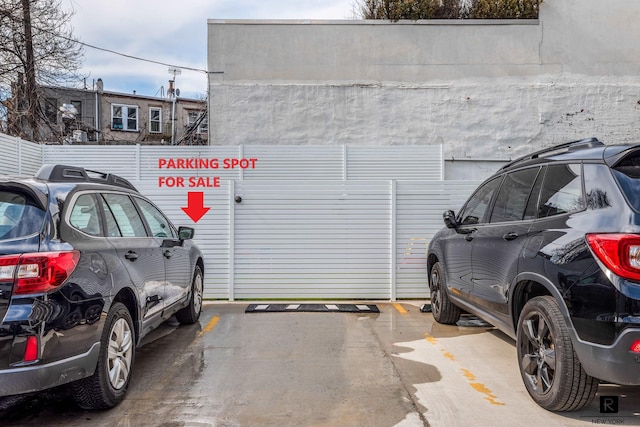 garage with uncovered parking and fence