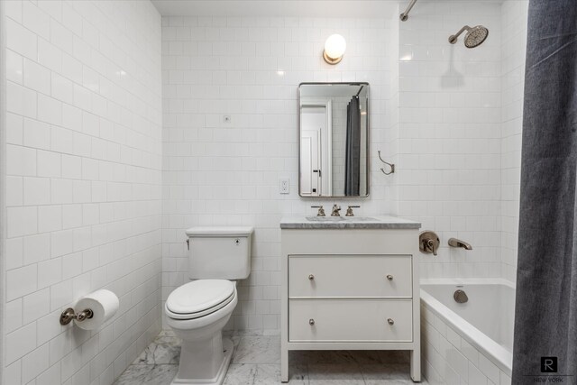 full bathroom with tiled shower / bath, toilet, vanity, and tile walls