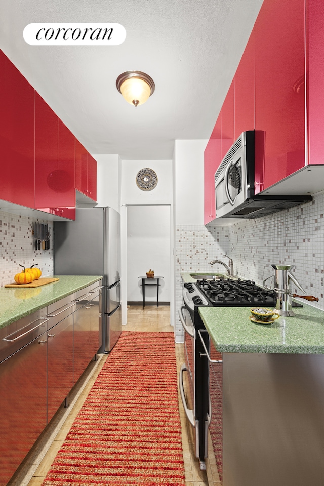 kitchen with red cabinetry, backsplash, and appliances with stainless steel finishes