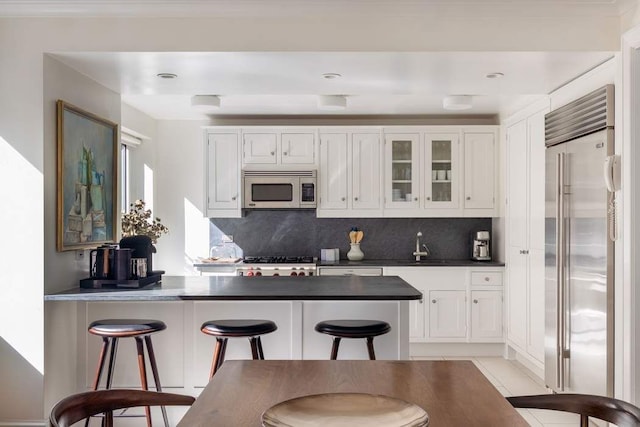 530 Park Ave Unit 5A, New York City, NY 10065 - kitchen with a peninsula, appliances with stainless steel finishes, white cabinets, and dark countertops