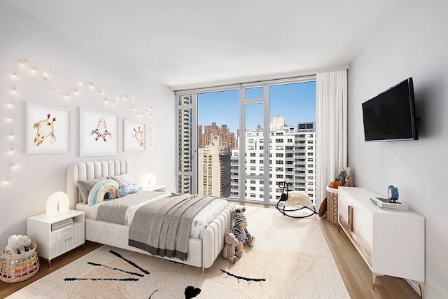 bedroom with floor to ceiling windows and wood finished floors