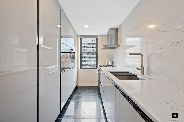 kitchen featuring gas range, recessed lighting, modern cabinets, wall chimney exhaust hood, and a sink