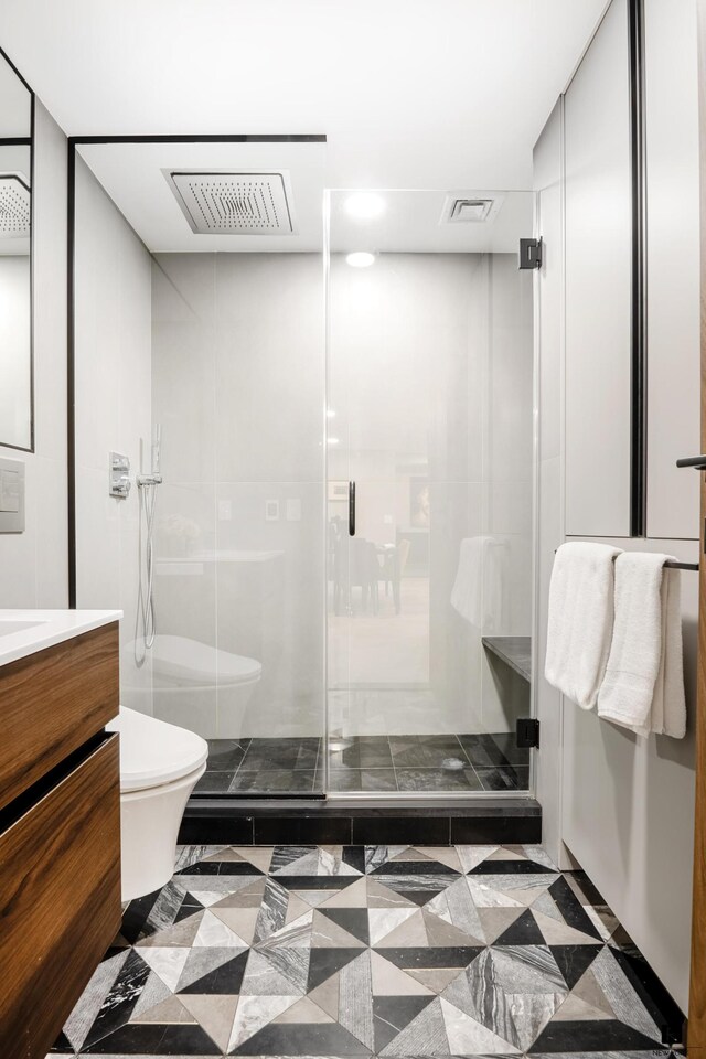 bathroom with visible vents, toilet, a stall shower, and vanity