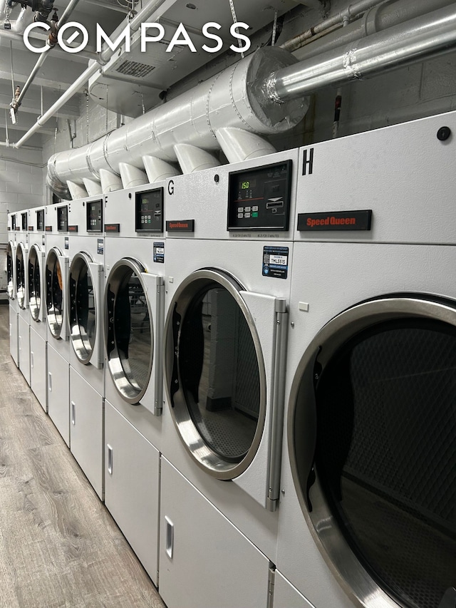 community laundry room featuring light wood-type flooring and washing machine and dryer