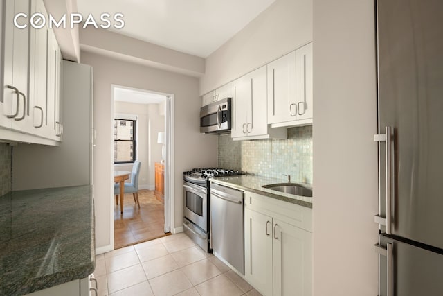 kitchen with a sink, stainless steel appliances, backsplash, and light tile patterned floors