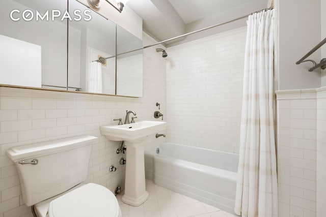 full bathroom with tile patterned floors, toilet, tile walls, and shower / bath combo with shower curtain