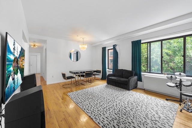 living room featuring a notable chandelier, baseboards, and wood finished floors