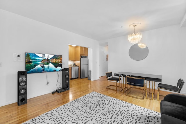 living area featuring a chandelier, baseboards, and light wood-style floors