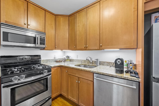 69 E 130th St Unit 2A, New York City, NY 10037 - kitchen with light wood-style flooring, a sink, stainless steel appliances, and light stone counters