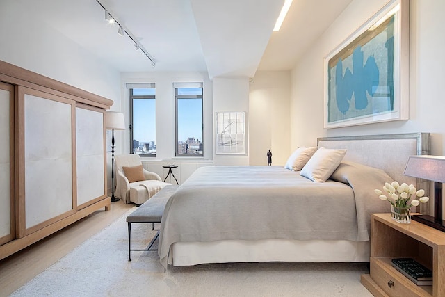 bedroom featuring track lighting and wood finished floors