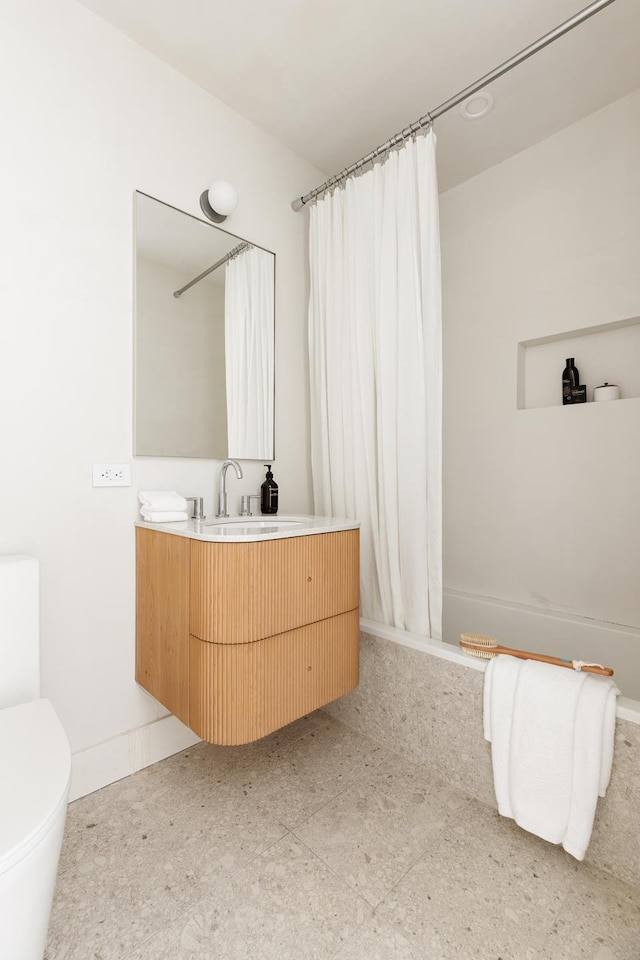 bathroom featuring baseboards, curtained shower, vanity, and toilet