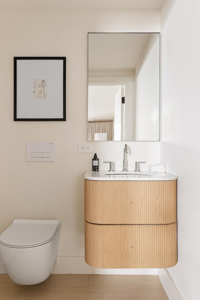 bathroom with toilet, vanity, and wood finished floors