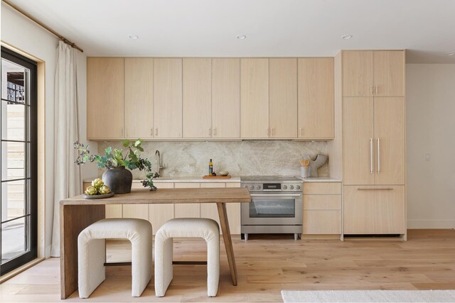 kitchen with light countertops, light brown cabinets, backsplash, and electric stove