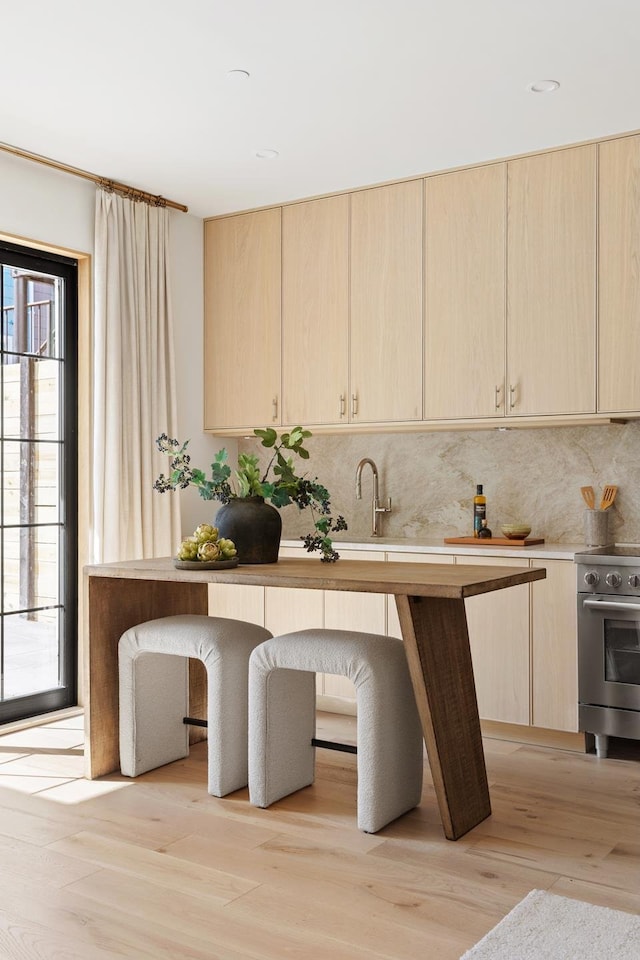 kitchen featuring light countertops, stainless steel range with electric stovetop, and light brown cabinets