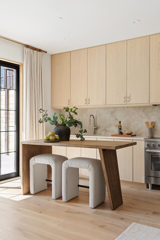 kitchen featuring light brown cabinetry, backsplash, and stainless steel electric range