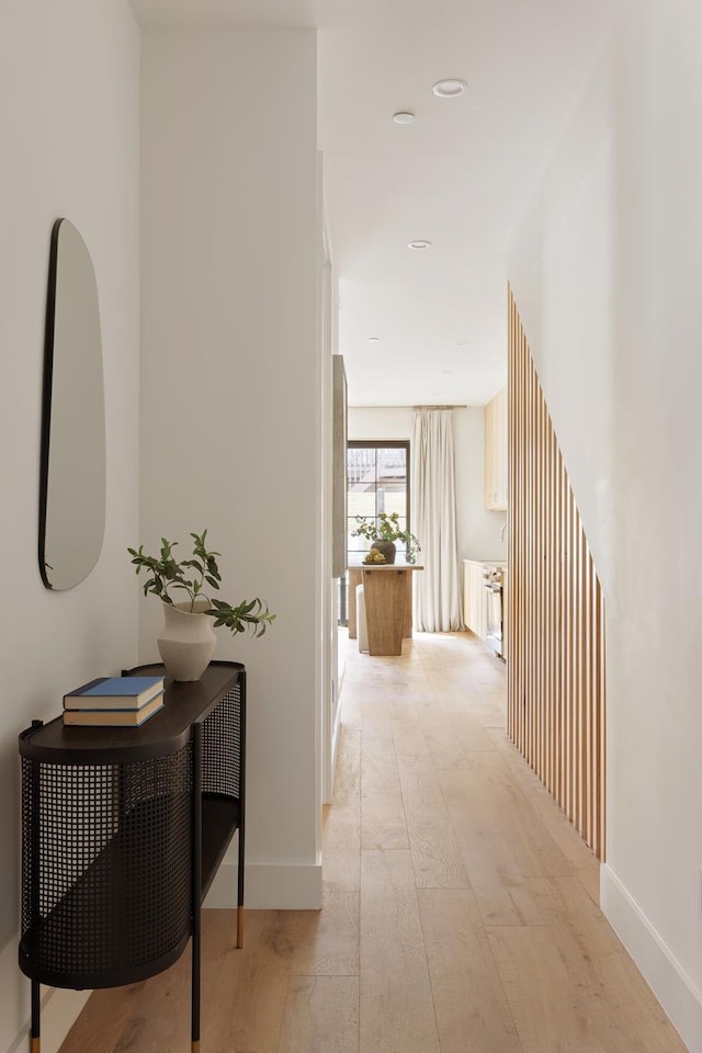 hallway featuring light wood finished floors and baseboards