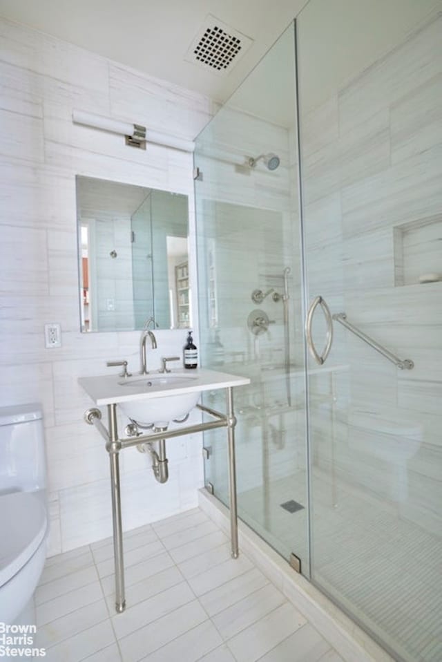 full bath featuring a stall shower, visible vents, toilet, tile patterned flooring, and tile walls