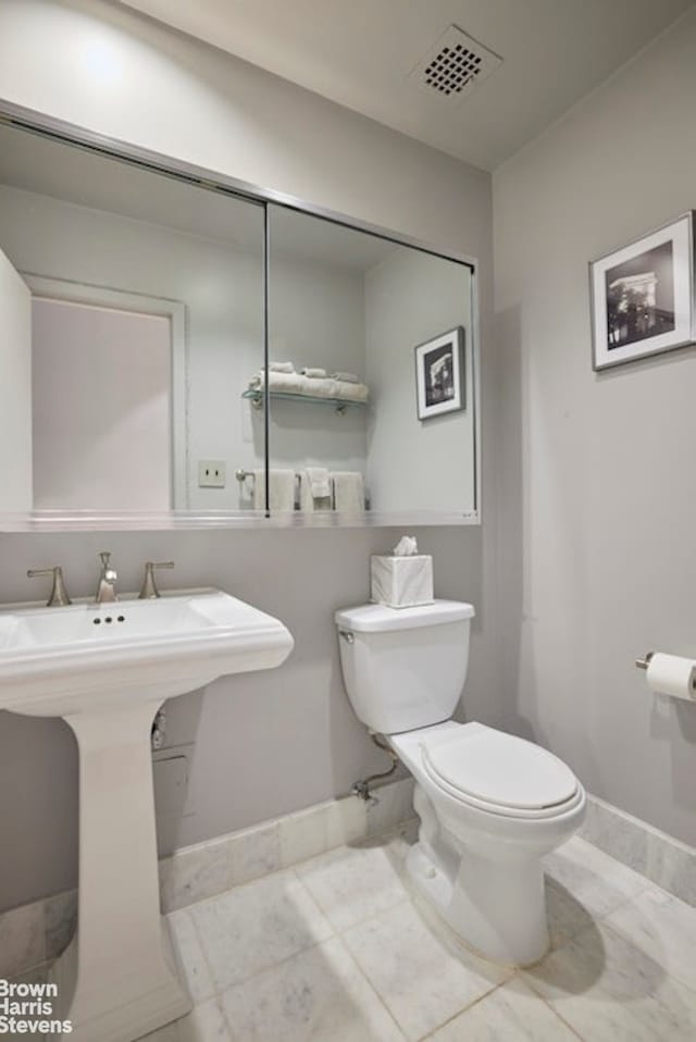 half bathroom with toilet, visible vents, and baseboards