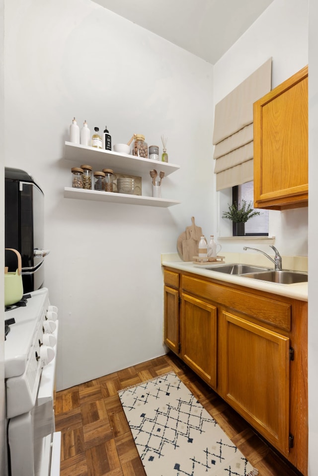 kitchen with light countertops, brown cabinets, open shelves, and a sink