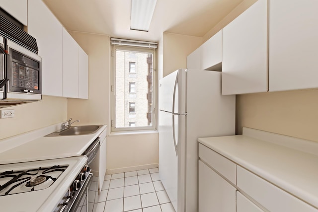 kitchen with light tile patterned floors, white appliances, a sink, white cabinets, and light countertops