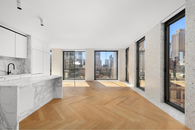 16 W 40th St Unit 21C, New York City, NY 10018 - kitchen featuring expansive windows, a skyline view, modern cabinets, white cabinets, and light stone countertops