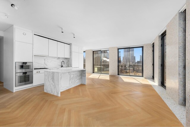 kitchen with a sink, white cabinets, a view of city, tasteful backsplash, and modern cabinets