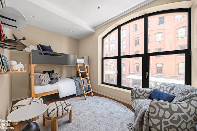 bedroom with multiple windows, wood finished floors, and baseboards