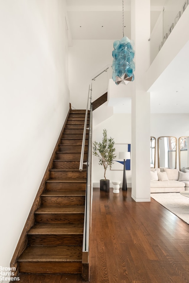 stairs featuring baseboards, a high ceiling, and wood finished floors